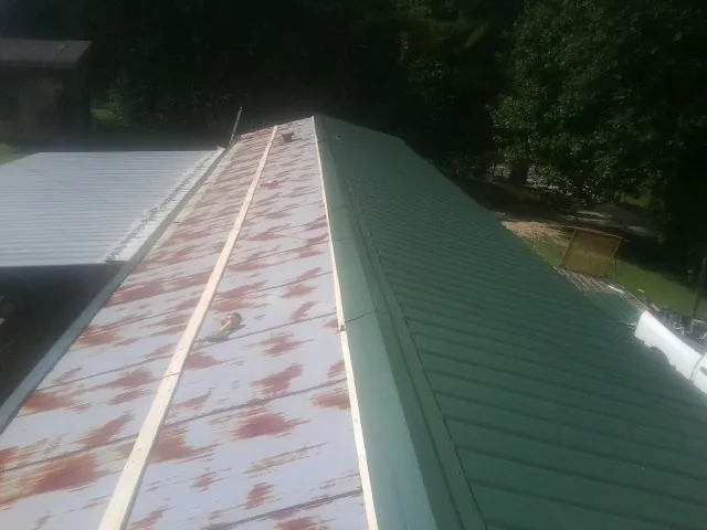 Old rusted panels beside newly installed green metal roofing — Wind Damage Roof Repair by Roofing Brothers in Ewell