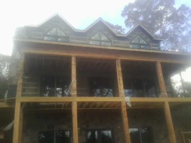 Dormers and porch framing on a large log home under construction — Roof Coating work by our crew in Ewell