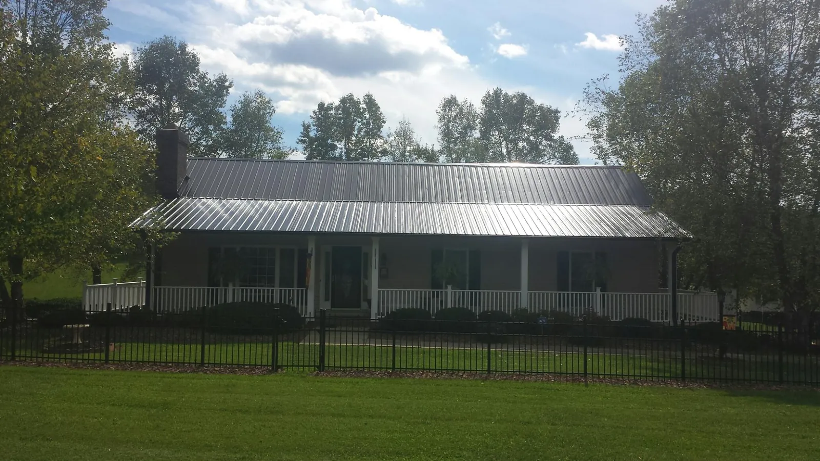 Gray metal roof on a brick ranch with a full width front porch — Gutter Guard Installation work by our crew in Ewell